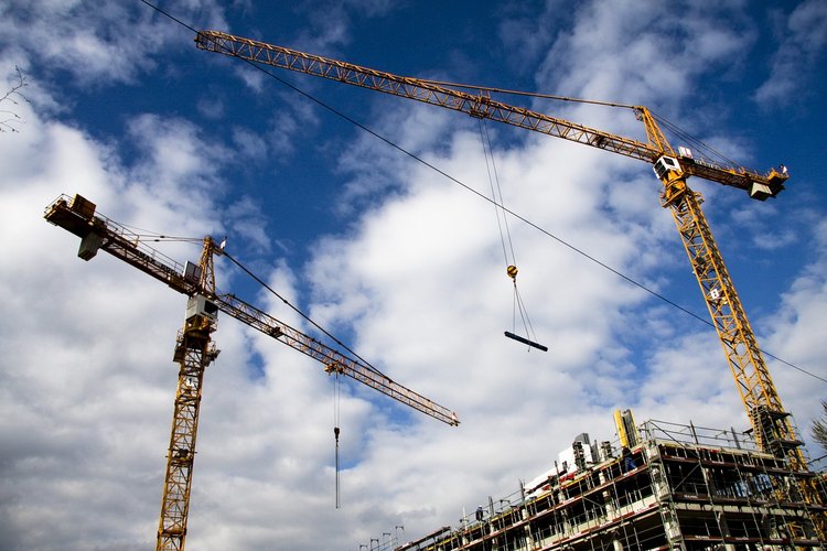 Photo de deux grues entourant un immeuble en chantier